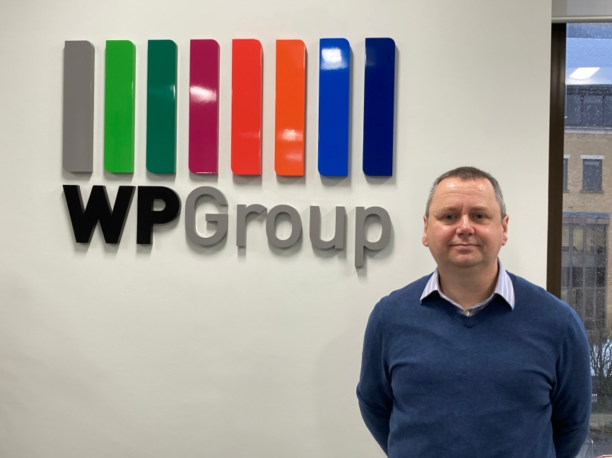 Donald Mackay standing next to a WP Group sign.